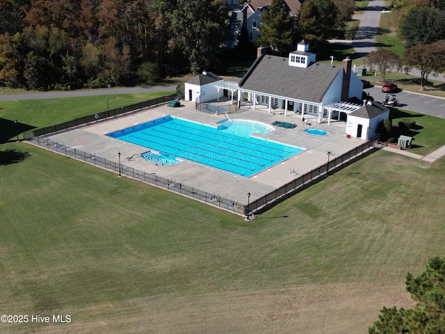 community pool featuring a patio area, a yard, and fence