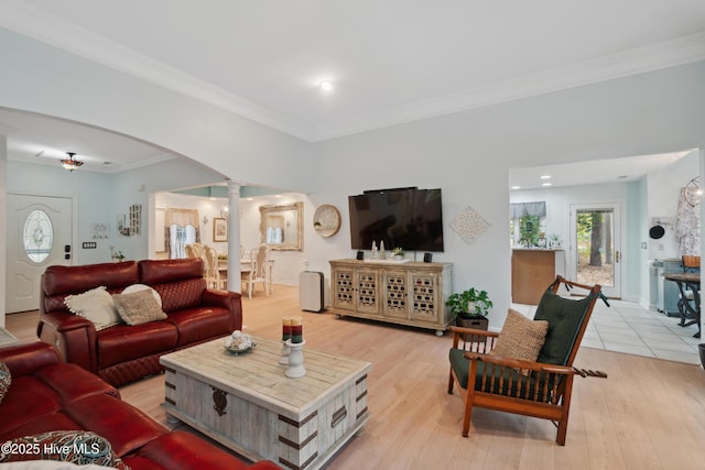 living area featuring arched walkways, crown molding, light wood-style floors, and ornate columns