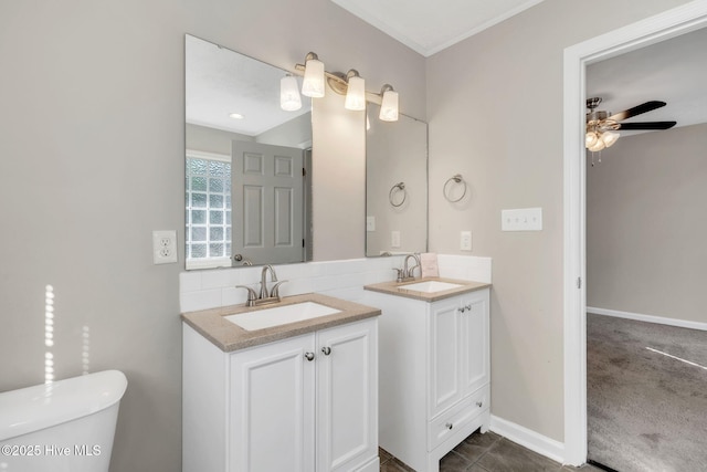 bathroom with a sink, toilet, two vanities, and a ceiling fan