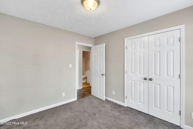 unfurnished bedroom with a closet, carpet flooring, a textured ceiling, and baseboards