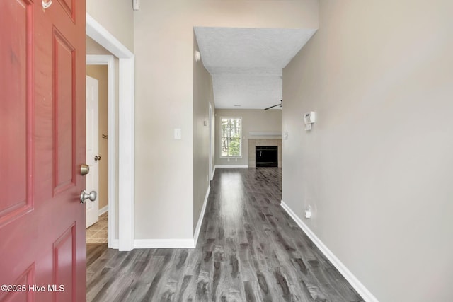 foyer entrance featuring a fireplace, wood finished floors, baseboards, and a textured ceiling