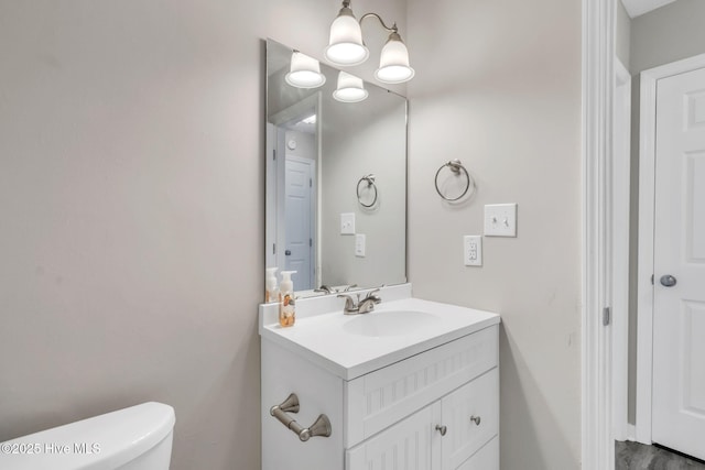 bathroom featuring toilet, an inviting chandelier, and vanity