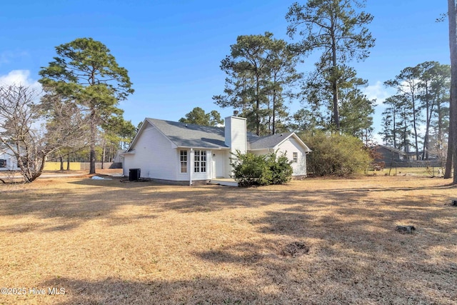 view of side of property featuring central air condition unit, a lawn, and a chimney