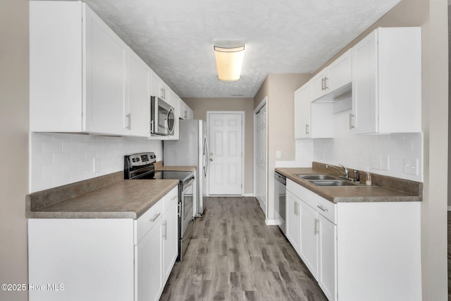 kitchen featuring a sink, appliances with stainless steel finishes, white cabinets, and light wood finished floors