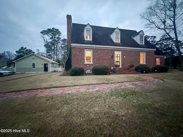 view of front of home featuring fence, a chimney, a front lawn, and brick siding