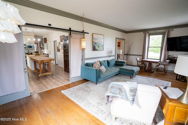 661 Main St, Swansboro, NC 28584 - living room with a barn door, wood finished floors, crown molding, and a chandelier