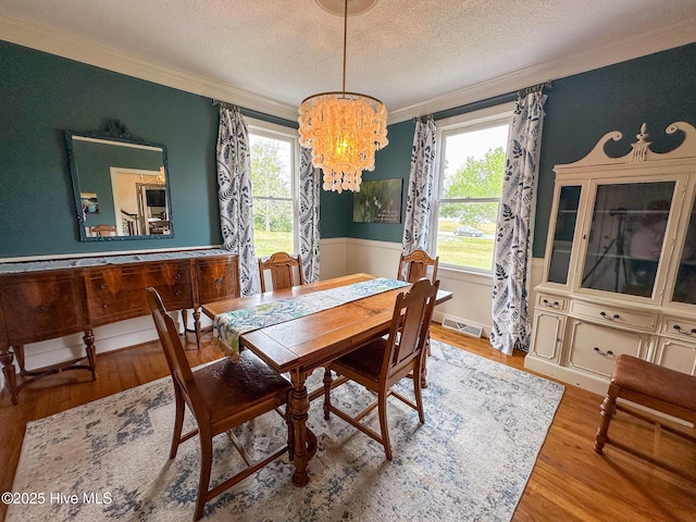 dining room featuring visible vents, a textured ceiling, crown molding, and a chandelier