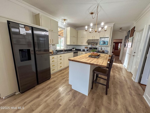 661 Main St, Swansboro, NC 28584 - kitchen with stainless steel appliances, under cabinet range hood, wooden counters, crown molding, and a sink