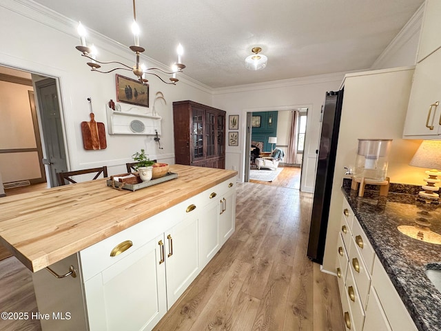 kitchen with crown molding, light wood finished floors, butcher block countertops, and white cabinetry