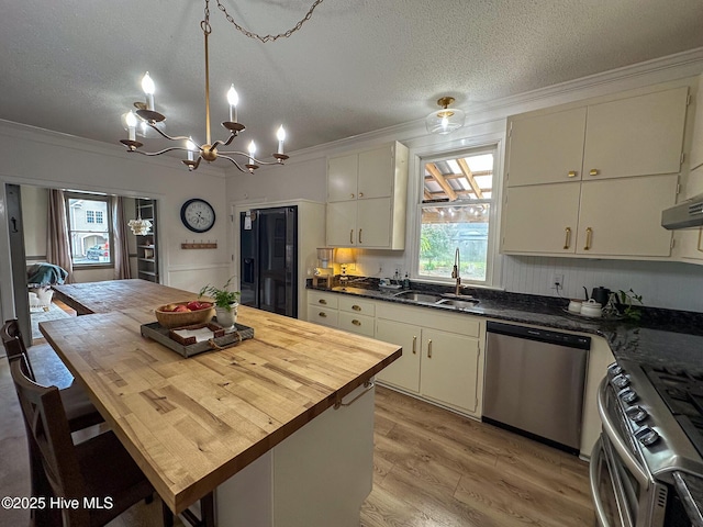 kitchen featuring a textured ceiling, appliances with stainless steel finishes, light wood-type flooring, a sink, and ornamental molding