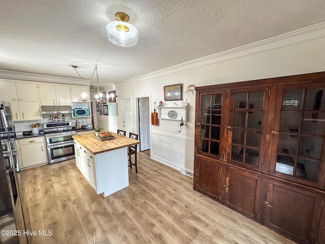 kitchen featuring ornamental molding, butcher block countertops, a textured ceiling, a notable chandelier, and double oven range