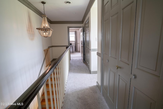 hall with light colored carpet, ornamental molding, an upstairs landing, and an inviting chandelier