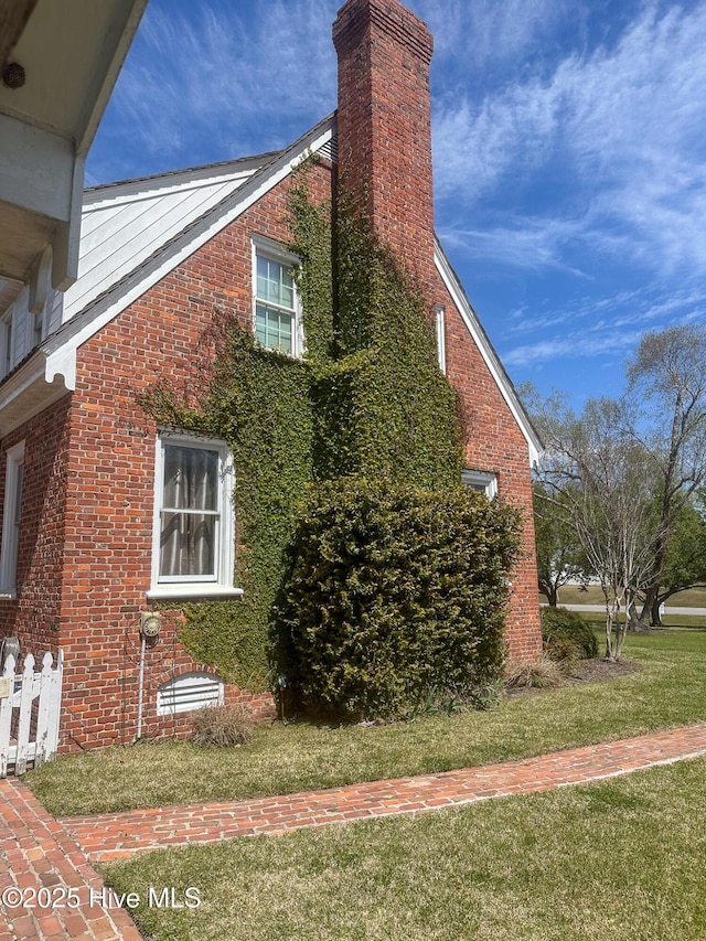 661 Main St, Swansboro, NC 28584 - view of side of property with brick siding, a chimney, and a yard