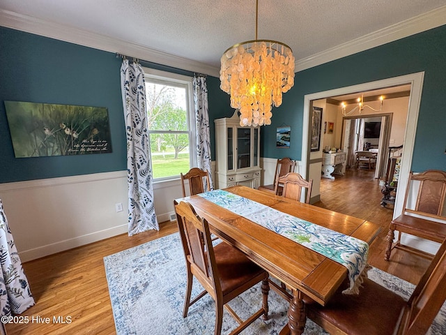661 Main St, Swansboro, NC 28584 - dining room with a chandelier, crown molding, light wood-style flooring, a textured ceiling, and baseboards