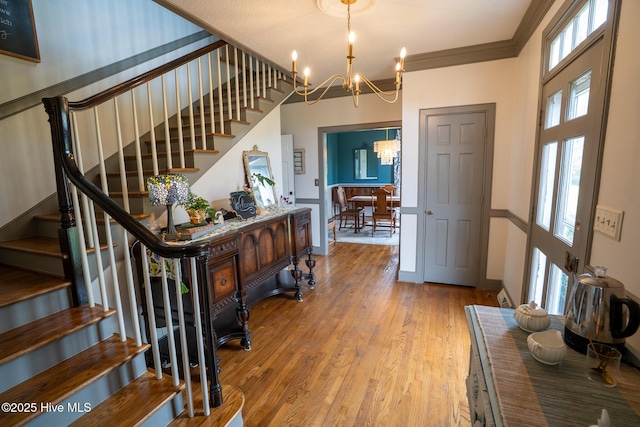 foyer with an inviting chandelier, plenty of natural light, wood finished floors, and stairway