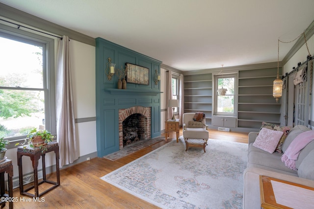 661 Main St, Swansboro, NC 28584 - living area with a brick fireplace, light wood-style flooring, crown molding, built in shelves, and baseboards