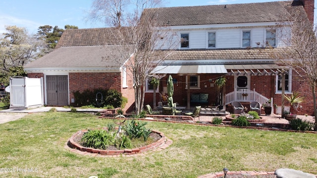 rear view of property with a yard, brick siding, and a patio area