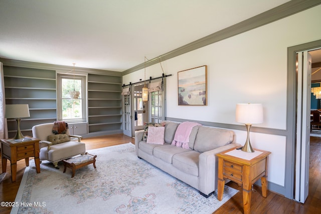661 Main St, Swansboro, NC 28584 - living room with wood finished floors, a barn door, crown molding, and built in shelves