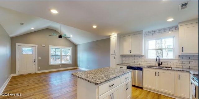 kitchen with a ceiling fan, a sink, backsplash, stainless steel dishwasher, and vaulted ceiling