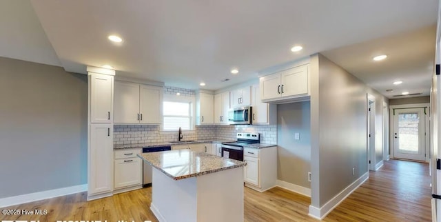 kitchen with light stone counters, stainless steel appliances, tasteful backsplash, and a sink