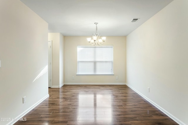 spare room featuring baseboards, visible vents, dark wood-style flooring, and a chandelier