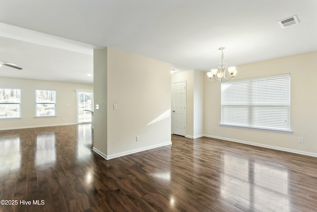 spare room with visible vents, baseboards, dark wood finished floors, and ceiling fan with notable chandelier