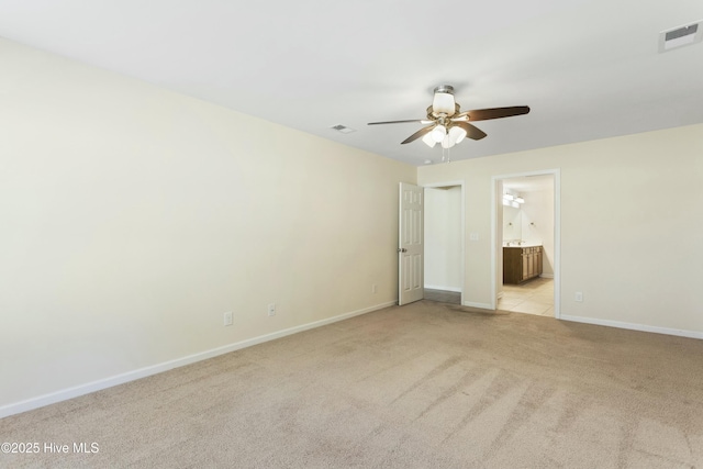 unfurnished bedroom with visible vents, light colored carpet, ensuite bath, and baseboards