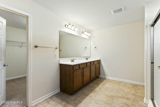 bathroom with double vanity, visible vents, baseboards, and a sink