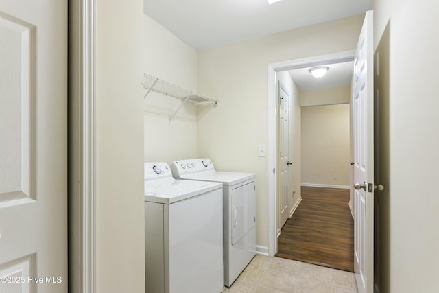 washroom featuring washer and dryer, laundry area, light tile patterned flooring, and baseboards