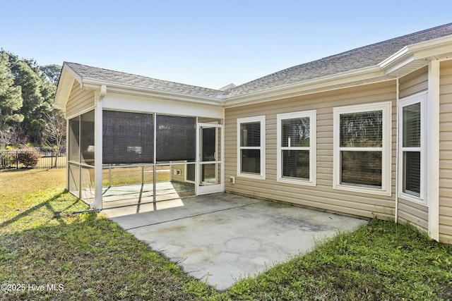 rear view of property featuring fence, a sunroom, a shingled roof, a patio area, and a lawn