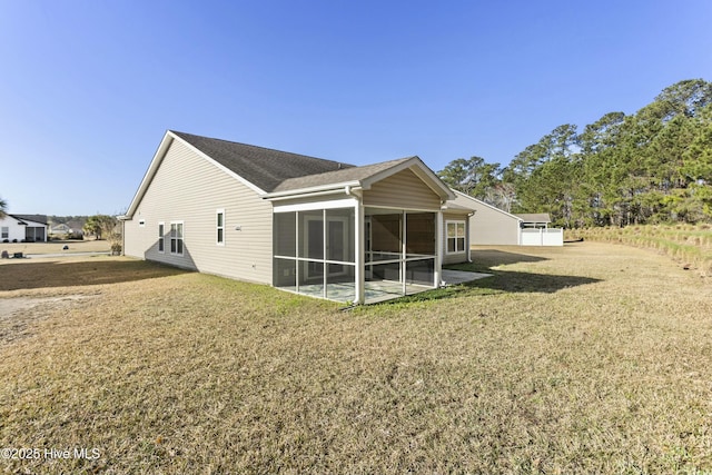 rear view of property with a lawn, a shingled roof, and a sunroom