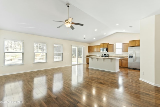 kitchen with open floor plan, appliances with stainless steel finishes, a breakfast bar area, and light countertops