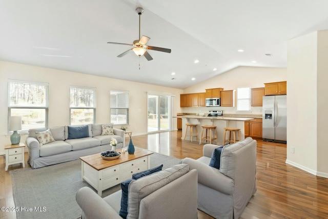 living room featuring a ceiling fan, baseboards, lofted ceiling, recessed lighting, and light wood-type flooring