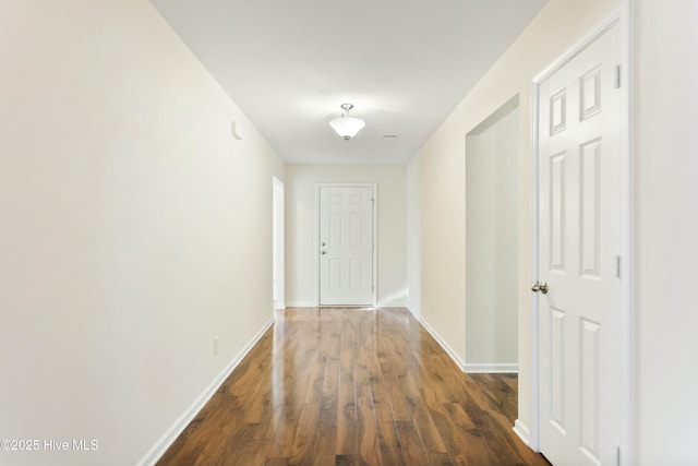 corridor featuring baseboards and dark wood finished floors