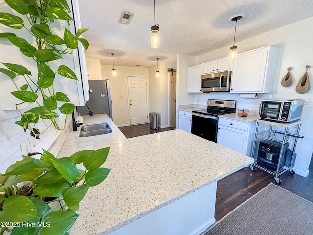 kitchen featuring visible vents, a sink, white cabinetry, stainless steel appliances, and decorative backsplash