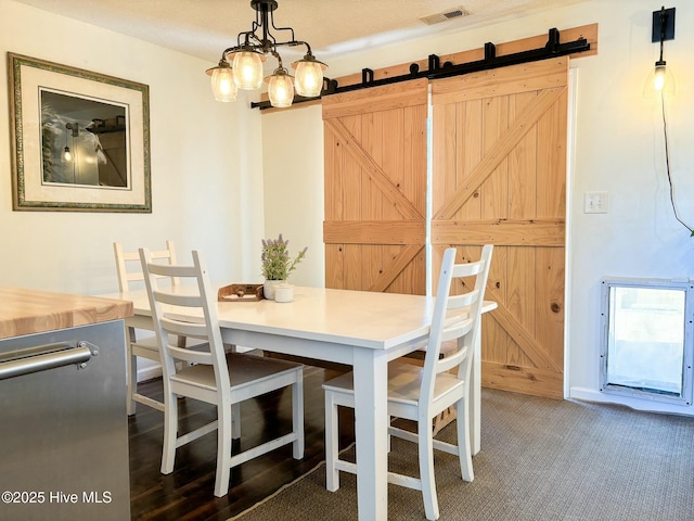 carpeted dining area with a barn door and visible vents