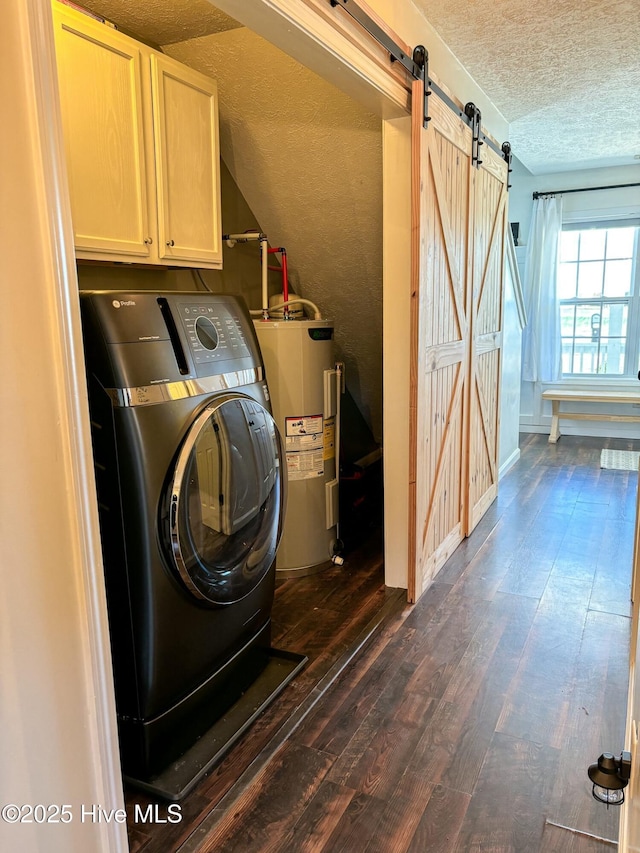 laundry room featuring a barn door, water heater, washer / dryer, cabinet space, and a textured ceiling