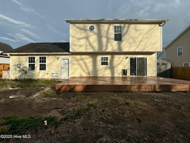 rear view of house featuring a deck and fence