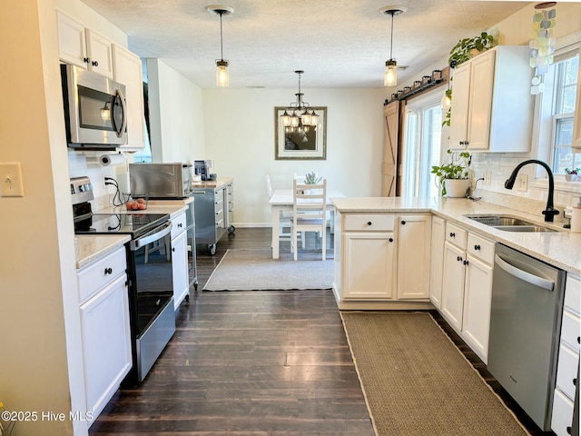kitchen with a peninsula, a sink, stainless steel appliances, dark wood-type flooring, and backsplash