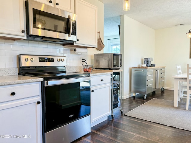 kitchen featuring visible vents, dark wood-style flooring, stainless steel appliances, decorative backsplash, and a textured ceiling