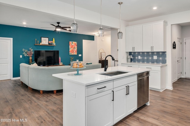 kitchen featuring decorative light fixtures, dishwasher, light countertops, wood finished floors, and a sink