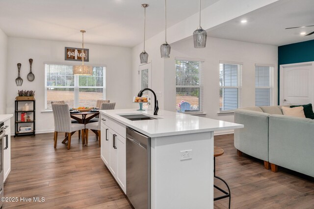 kitchen with a sink, a kitchen breakfast bar, dark wood finished floors, light countertops, and dishwasher