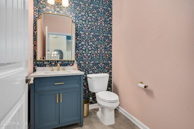 half bath with toilet, wallpapered walls, tile patterned flooring, baseboards, and vanity