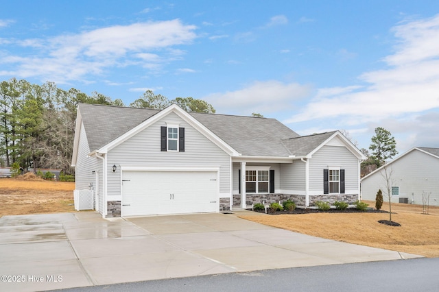 view of front of home featuring a front yard, driveway, a shingled roof, stone siding, and a garage