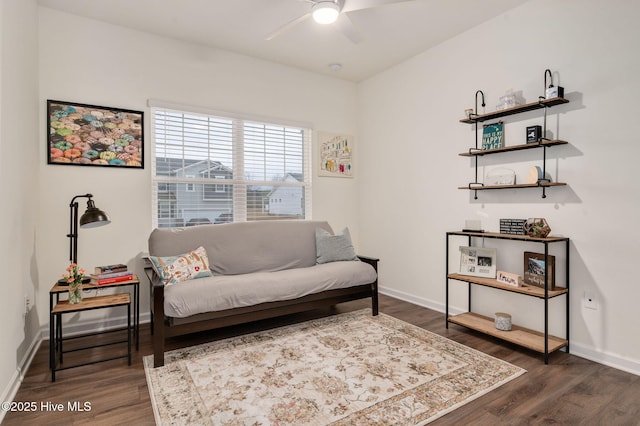 living area with baseboards, a ceiling fan, and dark wood-style flooring