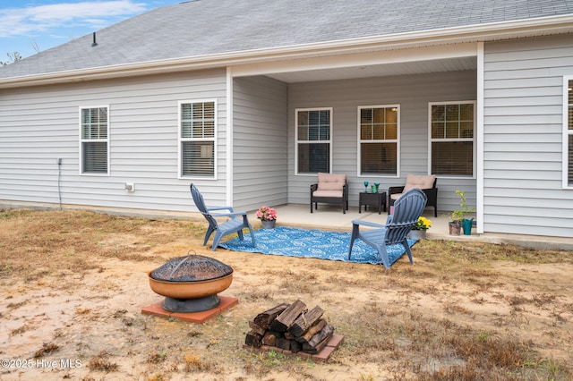 rear view of house featuring a patio, a fire pit, and roof with shingles