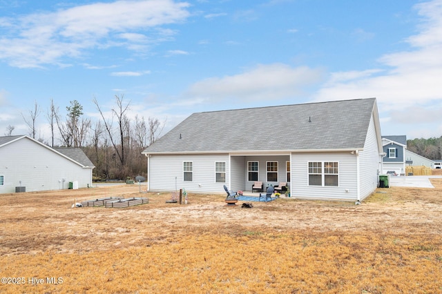 rear view of property with a yard, a patio, and roof with shingles