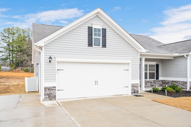 exterior space with driveway, stone siding, and roof with shingles