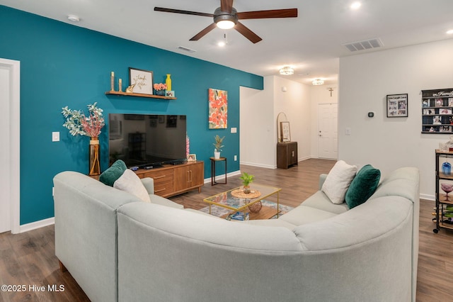 living room featuring visible vents, baseboards, ceiling fan, and wood finished floors