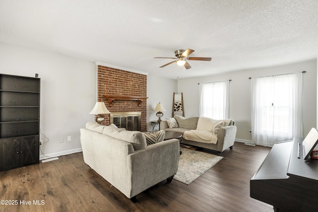 living room with a ceiling fan, baseboards, dark wood-type flooring, a textured ceiling, and a brick fireplace